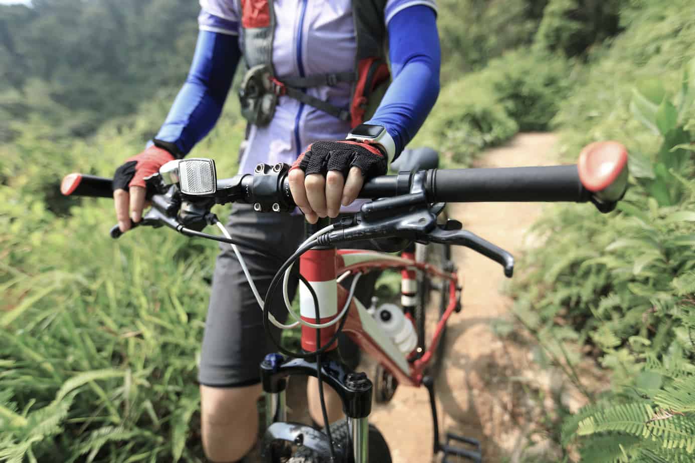 Cross country biking woman cyclist with mountain bike on tropical forest trail